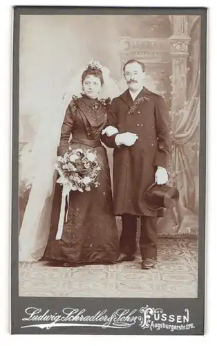 Fotografie Ludwig Schradler & Sohn, Füssen, Ehepaar im schwarzen Brautkleid und Anzug, Brautstrauss und Zylinder