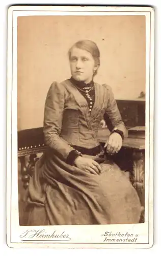 Fotografie J. Heimhuber, Sonthofen, Portrait hübsch gekleidete Dame am Tisch sitzend