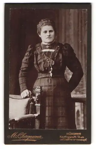 Fotografie M. Obergassner, München, Portrait junge Dame im karierten Kleid an Stuhl gelehnt