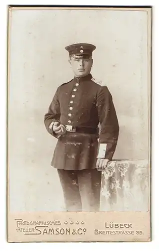 Fotografie Samson & Co., Lübeck, Soldat in Uniform mit Hand auf Tisch