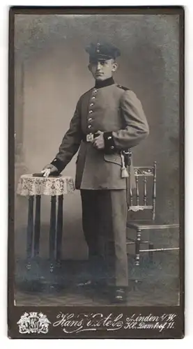 Fotografie Hans Kastel, Minden i. W., Portrait Soldat in Uniform am Tisch stehend