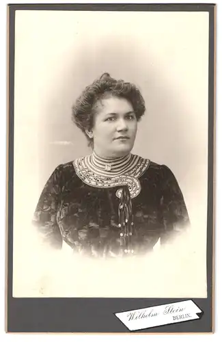 Fotografie Wilhelm Stein, Berlin, Junge Frau im dunklen Kleid mit zusammengestecktem Haar