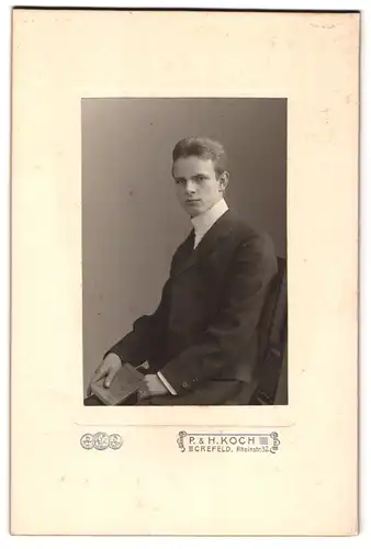 Fotografie P. & H. Koch, Crefeld, Mann im Anzug mit Buch