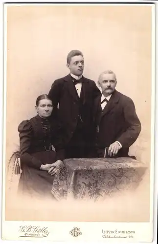 Fotografie G. B. Gäbler, Leipzig-Eutritzsch, Portrait bürgerliches Paar mit Sohn und Buch am Tisch