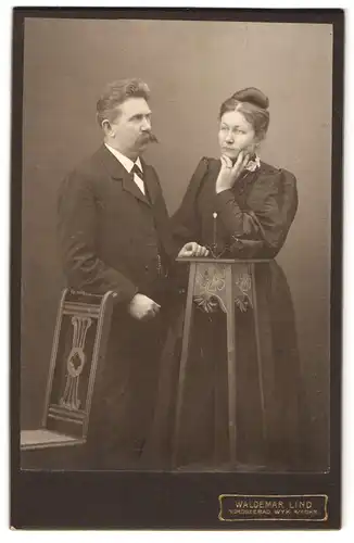 Fotografie Waldemar Lind, Wyk a / Föhr, Portrait bürgerliches Paar in eleganter Kleidung an Stehtisch gelehnt