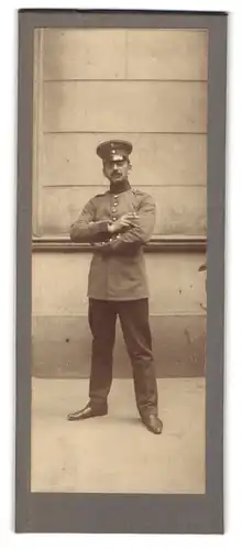 Fotografie unbekannter Fotograf und Ort, Portrait Soldat mit Zigarette vor einem Gebäude