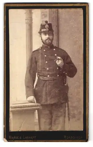 Fotografie Mange & Labhart, Rorschach, Portrait Soldat des schweizer Armee-Rgt. 82 mit Zigarre