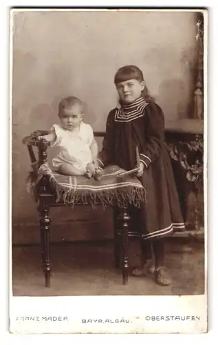 Fotografie Franz Mader, Oberstaufen / Bayr. Allgäu, Portrait süsses Baby im weissen Hemd auf Stuhl sitzend und Mädchen