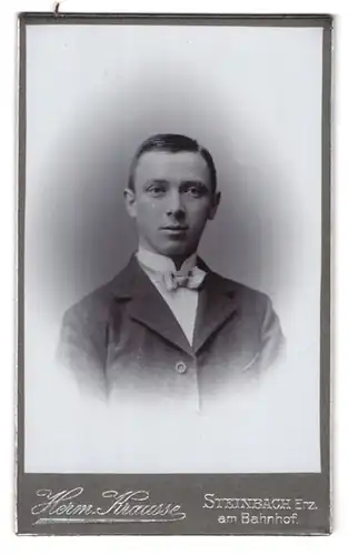 Fotografie Herm. Krausse, Steinbach /Erz., Am Bahnhof, Portrait junger Herr in Anzug mit Fliege