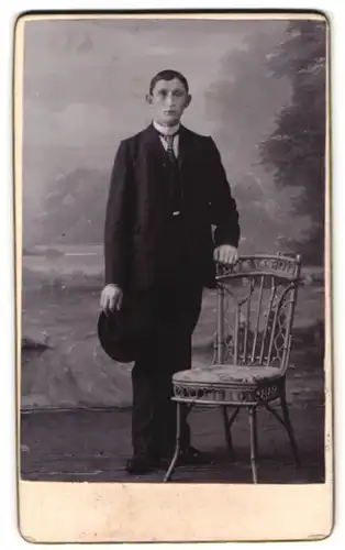 Fotografie unbekannter Fotograf und Ort, Portrait stattlicher junger Mann im Anzug am Stuhl stehend