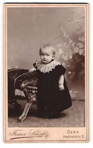 Fotografie Franz Scheffer, Gera, Adelheidstr. 2, Portrait blondes Kleinkind im bestickten schwarzen Kleidchen