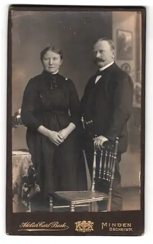Fotografie Carl Beste, Minden, Bäckerstrasse, Portrait elegant gekleidetes Paar am Stuhl stehend