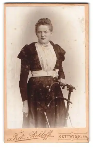 Fotografie Fritz Rohleff, Kettwig / Ruhr, Portrait junge Dame im eleganten Kleid an Stuhl gelehnt