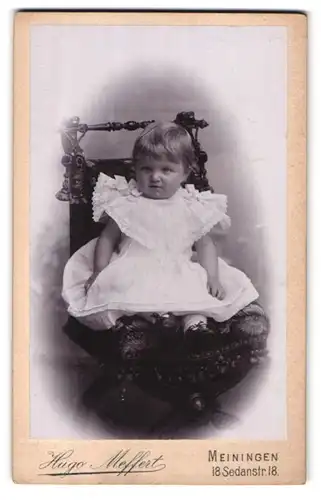 Fotografie Hugo Neffert, Meiningen, Sedanstrasse 18, Portrait niedliches Kleinkind im weissen Kleid auf Stuhl sitzend