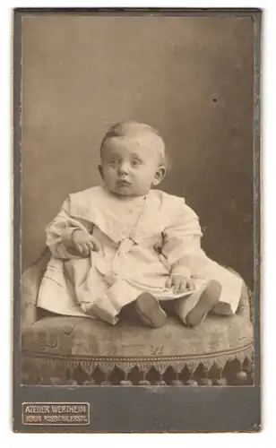 Fotografie Atelier Wertheim, Berlin, Rosenthalerstr., Portrait niedliches Kleinkind im modischen Kleid a. Sessel sitzend