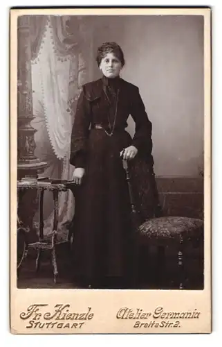 Fotografie Fr. Kienzle, Stuttgart, Breite Strasse 2, Portrait junge Dame im schwarzen Kleid an Stuhl gelehnt