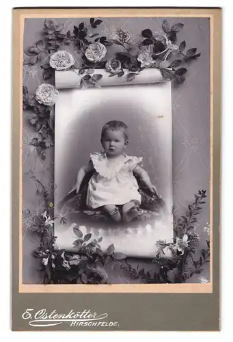 Fotografie E. Ostenkötter, Hirschfelde, Portrait niedliches Kleinkind im weissen Kleid auf Sessel sitzend