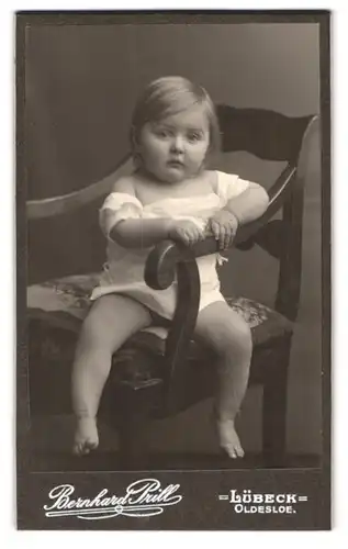 Fotografie Bernhard Prill, Lübeck, Breitestrasse 97, Portrait niedliches Kleinkind im weissen Hemd auf Stuhl sitzend