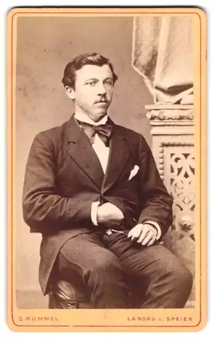 Fotografie C. Rummel, Landau, Portrait modisch gekleideter Herr auf Hocker sitzend