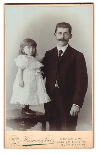 Fotografie Hermann Tietz, Berlin s.w., Leipziger Strasse 46, Vater und Tochter stehen an beziehungsweise auf einem Tisch