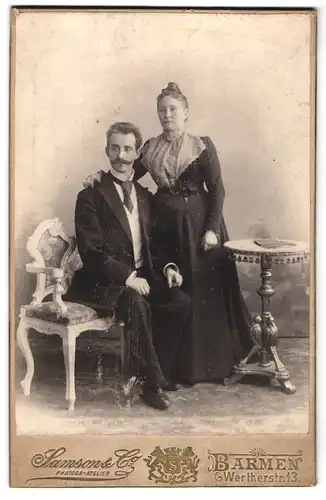 Fotografie Atelier Samson & Co., Barmen, Wertherstr. 13, Mann in Anzug mit Schnauzbart sitzend neben Frau in Tracht