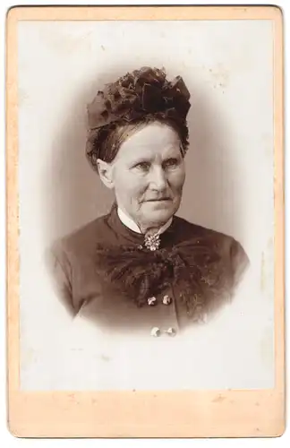 Fotografie Fotograf und Ort unbekannt, Alte Frau mit schweren Falten im Gesicht und hochgebundener Frisur