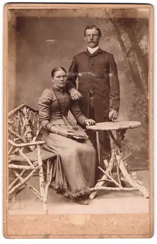 Fotografie unbekannter Fotograf und Ort, Portrait bürgerliches Paar in hübscher Kleidung am Tisch