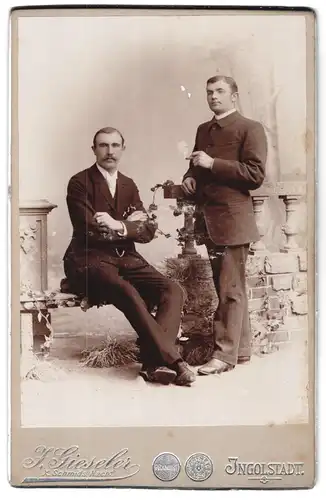 Fotografie J. Gieseler, Ingolstadt, Portrait zwei junge Herren in modischer Kleidung mit Zigarre