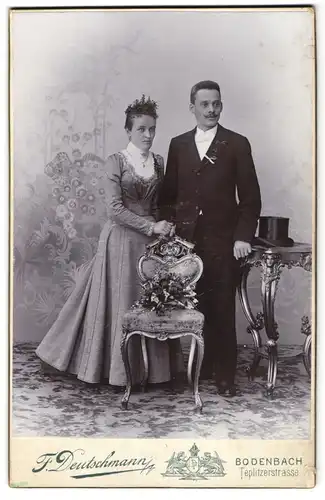 Fotografie F. Deutschmann, Bodenbach, Teplitzerstrasse, Ehepaar in schicker Kleidung lehen am Stuhl