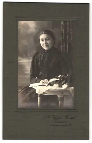 Fotografie F. Kuno Borst, Giessen, Johannesstrasse 11, Frau im schwarzen Kleid sitzt lesend an Tisch