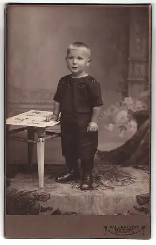 Fotografie Paul Hassert, Hannover, Welfenplatz 169, Junge steht an einem kleinen Tisch mit seinem Kinderbuch