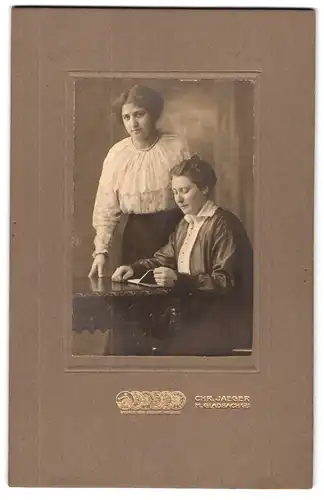 Fotografie Chr. Jaeger, M. Gladbach, Frau sitzt lesend am Tisch, die Schwester steht dahinter