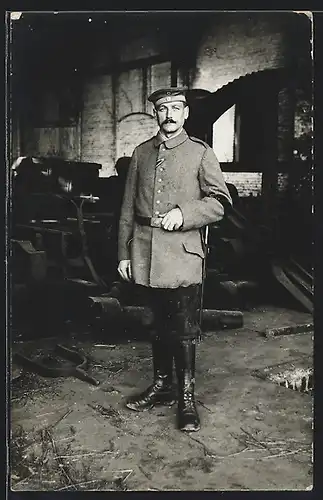 Foto-AK Soldat in Uniform Feldgrau mit Trauerflor Armbinde in der Werkstatt