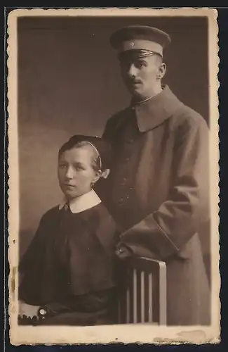 Foto-AK Soldat in Uniformmantel nebst seiner Frau als Rotkreuz Krankenschwester, 1918