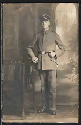 Foto-AK Soldat in Feldgrau Uniform vor einer Studiokulisse