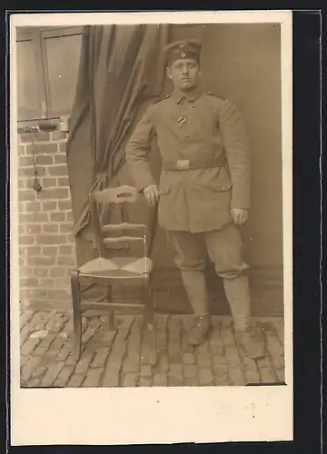 Foto-AK Soldat in Feldgrau Uniform mit eingestecktem Ordensband und Krätzchen