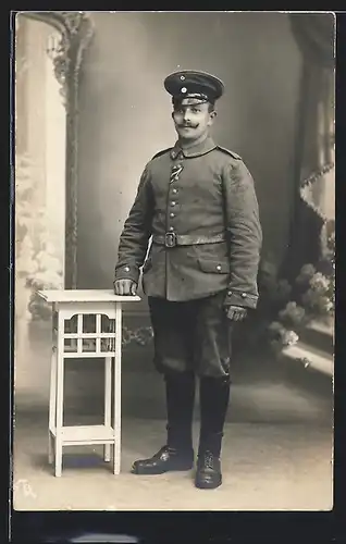 Foto-AK Uffz. in Feldgrau Uniform mit eingesteckten Ordensband, Ledgergamaschen