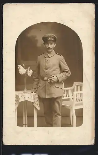 Foto-AK Soldat in Feldgrau Uniform mit Zigarre in der Hand