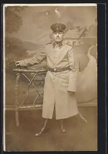 Foto-AK Soldat in Uniform Rgt. 28 mit Mantel vor einer Studiokulisse