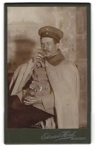 Fotografie Eduard Heid, Rastatt, Soldat in Uniform betrinkt sich im Atelier, Schnaps Flasche in der Hand