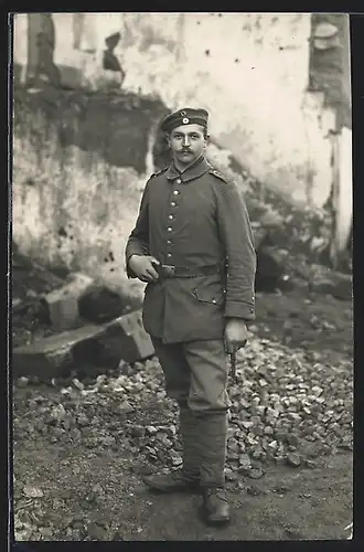 Foto-AK Soldat Hans in Feldgrau Uniform Rgt. 1 mit Bajonett vor Trümmern