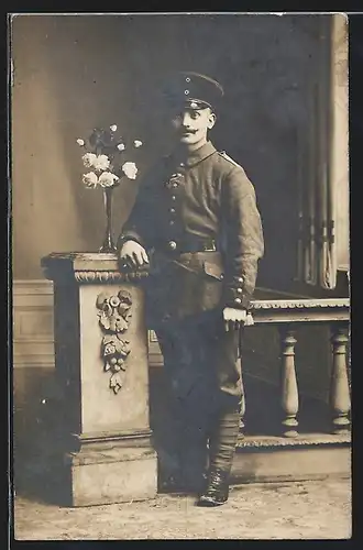 Foto-AK Soldat Ernst in Feldgrau Uniform mit eingestecktem Ordensband und Wickelgamaschen, 1917