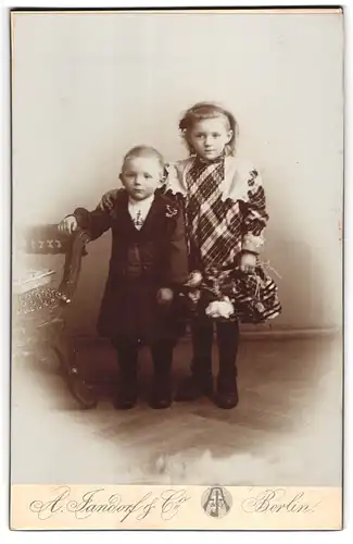 Fotografie A. Jandorf & Co., Berlin-S, Kottbusserdamm 1-2, Portrait Kinderpaar in hübscher Kleidung mit Blumen