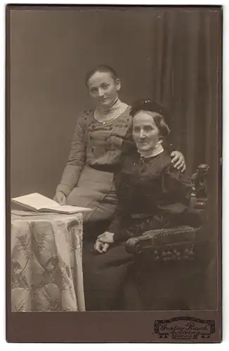 Fotografie Gustav Rasch, Schleswig, Stadtweg 32, Portrait ältere und junge Dame in hübscher Kleidung am Tisch