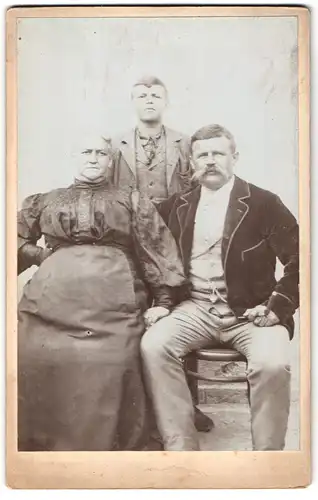 Fotografie unbekannter Fotograf und Ort, Portrait älteres Ehepaar mit einem Sohn in modischer Kleidung