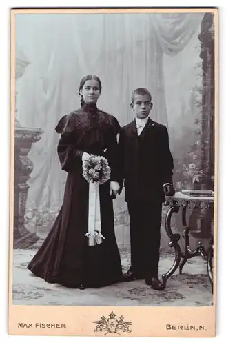 Fotografie Max Fischer, Berlin-N, Invaliden-Strasse 164, Portrait Mädchen und Knabe in schwarzer Kleidung mit Blumen