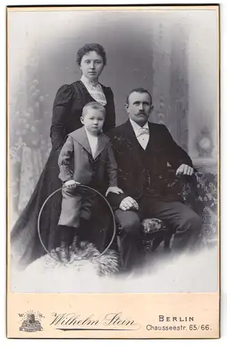 Fotografie Wilhelm Stein, Berlin, Chausseestrasse 65-66, Portrait bürgerliches Paar und Sohn mit Reifen