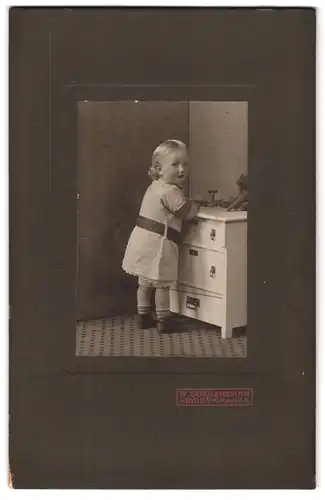 Fotografie W. Schölermann, Heide i. H., Markt 9, Portrait niedliches Kleinkind im gestreiften Kleid