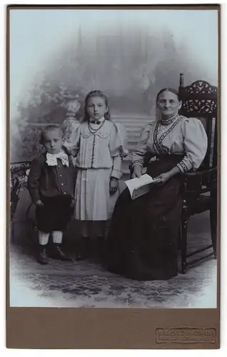 Fotografie Willibald Hartmann, Gross-Schönau i / S., Portrait bürgerliche Dame mit Buch auf Stuhl sitzend & zwei Kinder