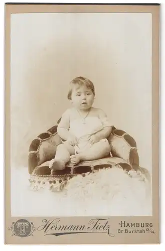 Fotografie Hermann Tietz, Hamburg, Gr. Burstah 12-14, Portrait niedliches Kleinkind im weissen Hemd auf Sessel sitzend